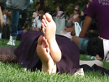 Woman Sunbathing Her Magical Feet As She Resting On The Grass In Public