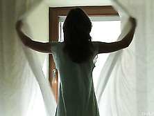 Long Haired Brunette Pulls Open Her Drapes Before Gazing Out Window,  Lies Back On Bed